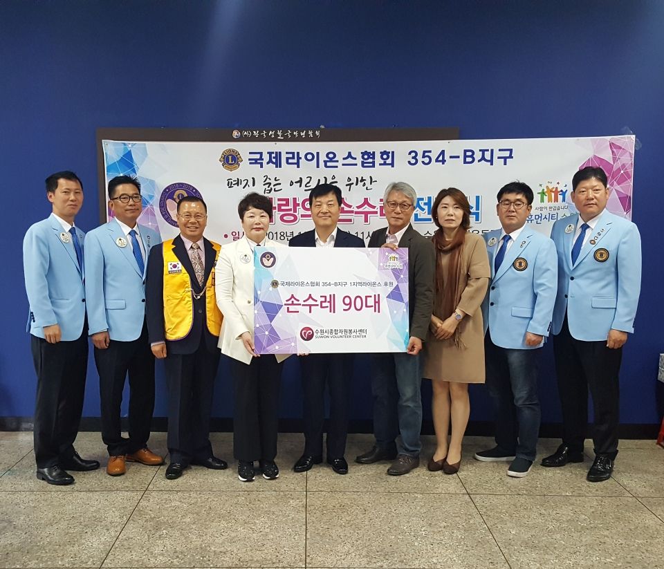 신화균 수원시 복지여성국장(가운데)이 김혜옥 수원시 국제라이온스클럽 354-B지구 1지역 부총재(왼쪽 세 번째)와 김주현 수원시 종합자원봉사센터 상임이사(오른쪽 네 번째)와 손수레를 전달하고 기념촬영을 하고 있다.