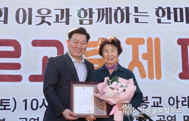 박승원 광명시장이 지난 1일 개봉교 아래 목감천 일대에서 열린 ‘제8회 광명2동 한마당 축제’에 참석해 어르신 환경봉사대 참여 어르신에게 시창 표창을 수여하고 기념사진을 촬영하고 있다.